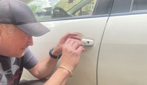 Meistras atrakinėja balto Toyota Prius automobilio duris